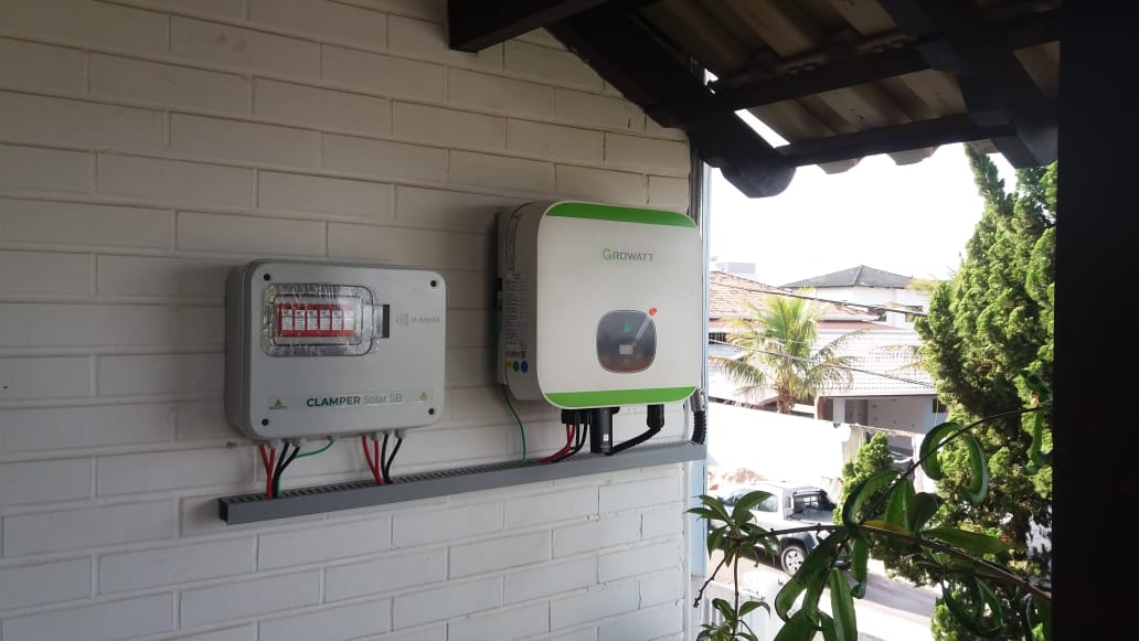 Inversor e quadro de string instalados em parede de varanda residencial